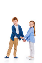 beautiful redhead siblings holding hands and smiling at camera isolated on white