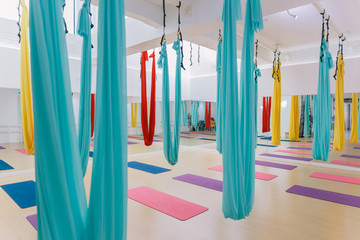 Empty flying yoga studio with colourful hammocks with colourful yoga mats on wooden texture floor at yoga studio in Bangkok, Thailand.