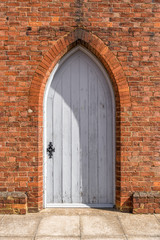 Old retro style white closed door on red brick wall of English building