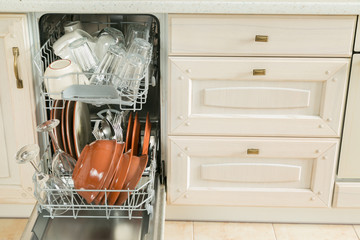 Dishwasher full with clean dishes in kitchen background
