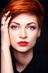 Portrait of a beautiful young red-haired woman with short hair on a dark background