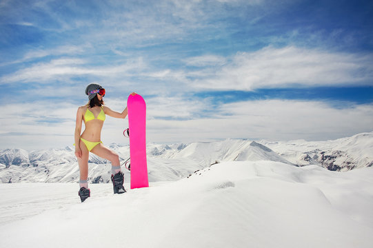Attractive sexy woman in swimsuit and helmet with a snowboard