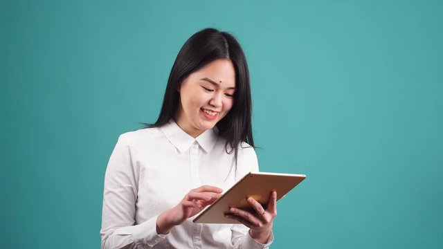 Young Asian Businesswoman Using Tablet Computer on Blue Background.