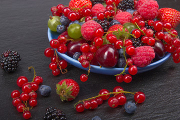 Various summer Fresh berries in a bowl on rustic wooden table. Antioxidants, detox diet, organic fruits.