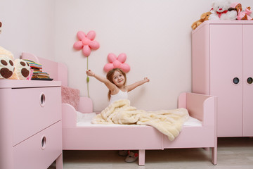 little girl wakes up in the morning in the children's bedroom