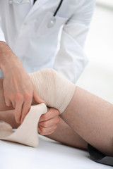 Fototapeta premium doctor bandaging patient knee