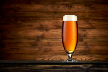 Glass of cold beer on wooden background