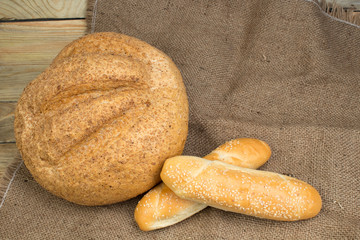 Many mixed breads and rolls of baked bread, on wooden background, food closeup.