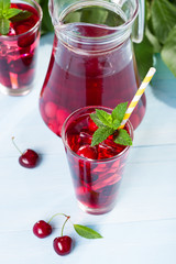 Glass of cherry juice on blue wooden table