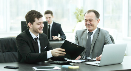 adult businessman discussing financial documents with a young colleague.