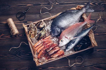 Papier Peint photo Poisson Poissons et fruits de mer espagnols frais dans une boîte en bois sur une table en bois