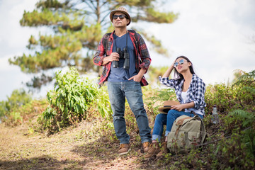 Thoughtful hiking couple looking away while relaxing in forest