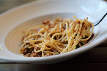 spaghetti Bolognese with minced beef and tomato sauce garnished with parmesan cheese and basil , Italian food
