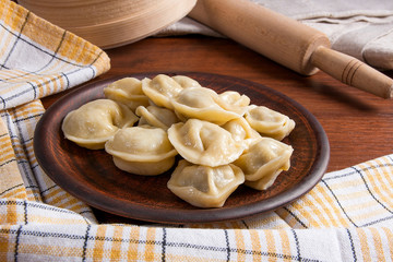 Boiled Ukrainian meat dumplings or ravioli on wooden background.