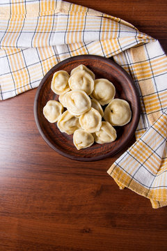 Boiled Ukrainian meat dumplings or ravioli on wooden background.