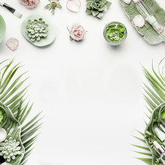 Fototapeta na wymiar Modern natural skin care equipment with roses, succulents, facial mist water spray and green tropical leaves on white background, top view, flat lay, frame. Beauty concept