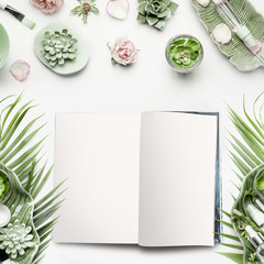 Fototapeta na wymiar Mock-up of open magazine or catalog for beauty and cosmetic products. Modern natural skin care equipment with roses, succulents, facial mist water spray and green tropical leaves on white background