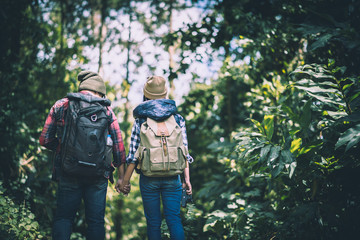 Young couple walking with backpacks in forest. Adventure hiking, Enjoy holidays together,