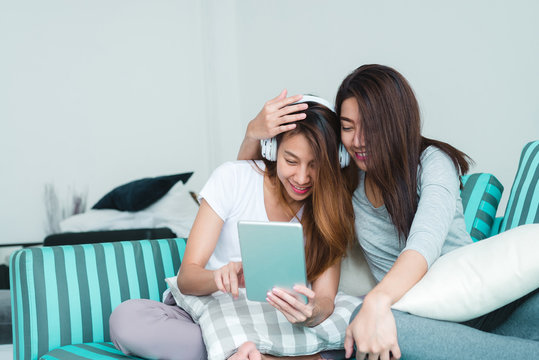 Beautiful young asian women LGBT lesbian happy couple sitting on sofa buying online using tablet in living room at home. LGBT lesbian couple together indoors concept. Spending nice time at home.