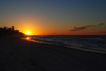 Fototapeta na wymiar Sunset on the beach in Cuba. Orange sun on the horizon.