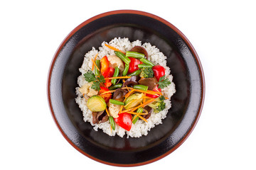 Rice with vegetables in a black bowl on a white background. Garnish.