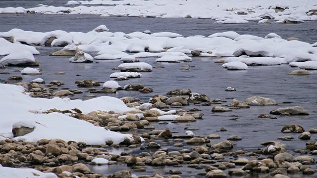 Stones with snow caps in the water of Altai Biya river in winter season