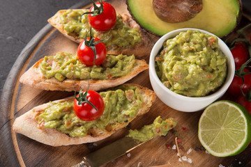 Guacamole with bread and avocado on stone background