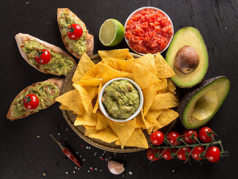 Guacamole with bread and avocado on stone background
