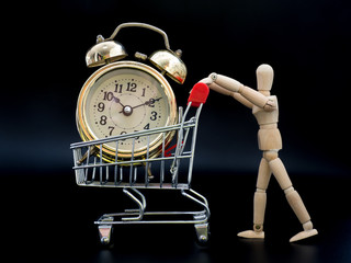 Puppets are holding a shopping cart. There is a golden vintage clock inside on black background....