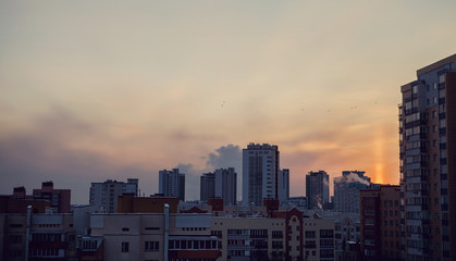 Panoramic view of beautiful yellow golden sunset over city. Evening urban landscape covered in setting sun beams.