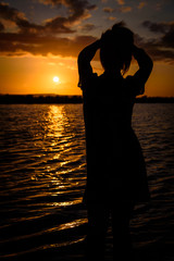 Silhouette of free woman enjoying freedom feeling happy at sunset on the beach