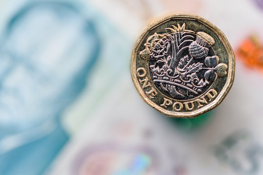 A close up of a British Pound Coin on top of bank notes