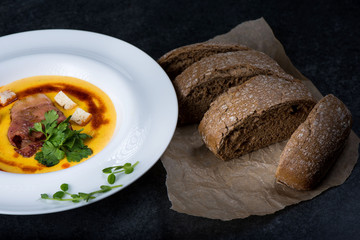 An appetizing pumpkin soup is served in a white plate in a restaurant