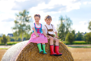 Two kids, boy and girl in traditional Bavarian costumes in wheat field