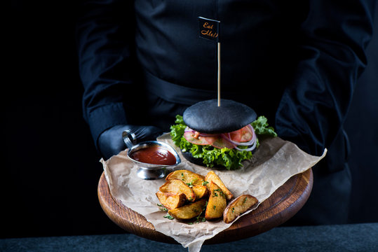 Black burger on a wooden plate