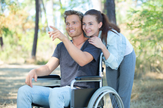 loving couple in wheelchair walking outdoors