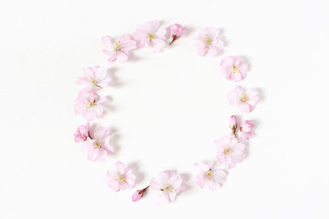 Stock photo de style. Printemps, composition florale de scène féminine de Pâques. Motif de couronne de cadre rond fait de fleurs de cerisier japonais roses. Fond blanc. Mise à plat, vue de dessus.