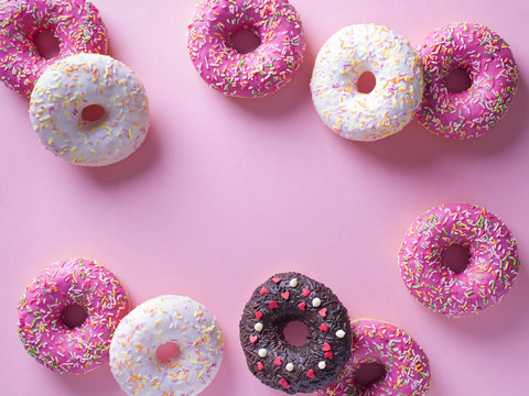 Pink and white donuts with celebration item on pink background