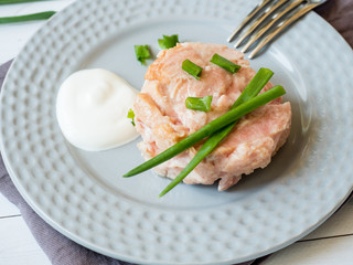 Canned tuna in its own juice with green onions on a plate. selective focus