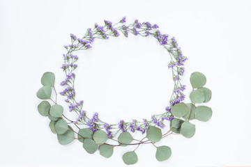 Flower round frame with fresh branches of wildflowers and eucalyptus leaves isolated on white background, flat lay and top view