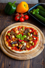 Fresh homemade pizza with different vegetables on a wooden background