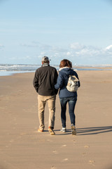 A woman and a man are walking on a sunny day along the beach in Katwijk. Netherlands