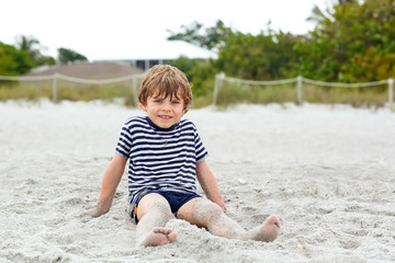 Little kid boy having fun on tropical beach