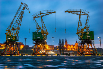 Historical harbor cranes on riverside boulevards in the evening, after a spring downpour