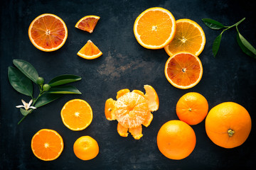 Fresh orange fruits and slices on a black metal tray