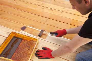 Painting a terrace board impregnation water proofing. Carpenter painting wood.