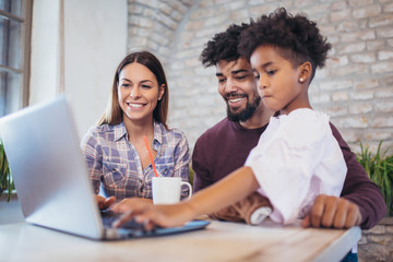 Girl and mixed race parents use laptop at home