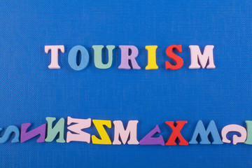 Fototapeta na wymiar TOURISM word on blue background composed from colorful abc alphabet block wooden letters, copy space for ad text. Learning english concept.