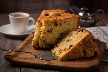 cup of coffee and slices of home made cake with raisins on wooden plate