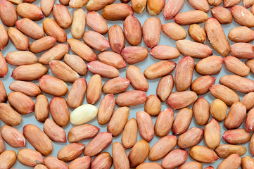Background of peeled peanuts scattered on a white table close-up